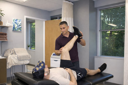 Physical therapist assessing hip flexion range during a hip impingement evaluation at a Wayne, NJ physical therapy clinic.