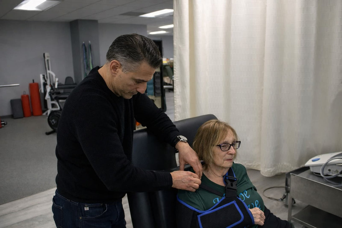 Dr. Rob Letizia checking the shoulder of a patient wearing a post-operative sling during physical therapy in Wayne, NJ.