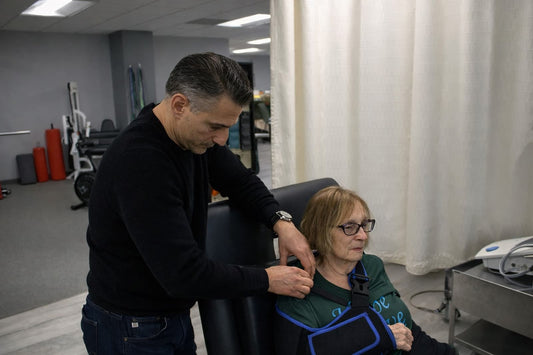Dr. Rob Letizia checking the shoulder of a patient wearing a post-operative sling during physical therapy in Wayne, NJ.